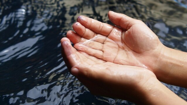 Boy's hand scooping transparent water in the spring for ablution. Clear water in the palm of a boy's hand.