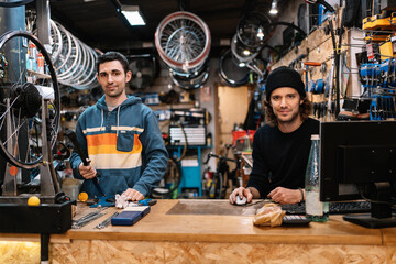 Cheerful mechanics working in bicycle repair service workshop