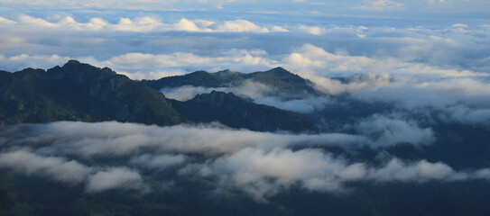 Fog and clouds surrounding green hills and mountains in Entlebuch, Lucerne Canton.