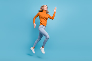Full body photo of positive pretty nice woman jump up run empty space smile isolated on blue color background