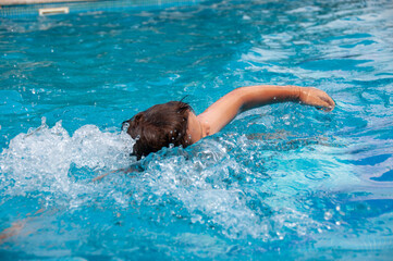 Teen boy swimming crawl in the pool