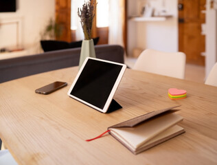 Tablet and notebook placed on wooden table