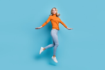 Fototapeta na wymiar Full length photo of cheerful young woman look empty space jump up air isolated on pastel blue color background