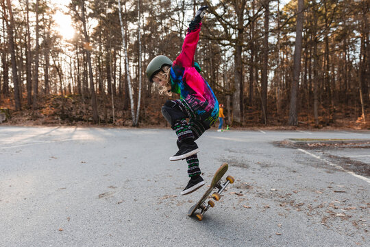 Energetic girl jumping with skateboard in park