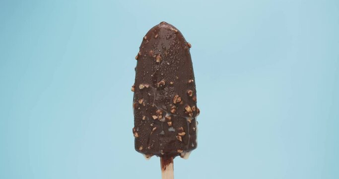 Time-lapse ice cream popsicle stick Chocolate melt isolated on a blue background, Close-up detail Front view.