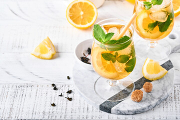 Traditional iced tea with lemon and ice in tall glasses on marble table background Iced tea with...