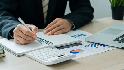 Businessman looking at the company's financial graph document for analysis and guidance. Asian business accountant or banker is calculating savings, finance and economy concepts through financial conc
