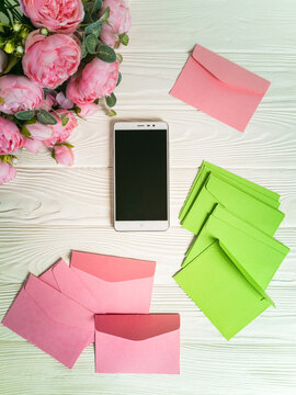 Top view of smartphone screen, flowers and letter envelopes