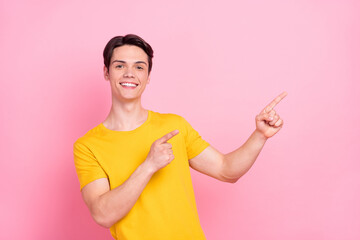 Photo of young guy happy positive smile point fingers empty space direct way ad suggest isolated over pink color background