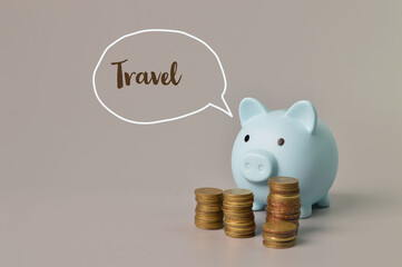 Stack of coins and piggy bank with text TRAVEL.