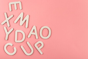 Wooden alphabet letters on pink paper background.