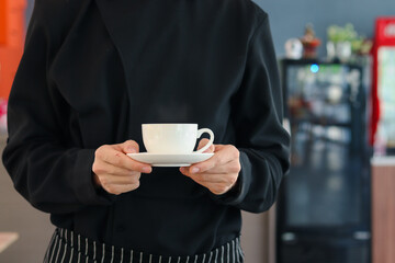 Barista hands holding a cup of hot coffee in the cafe shop, waiter staff serving coffee to customer in coffee shop counter bar, man holding beverage drink in restaurant.