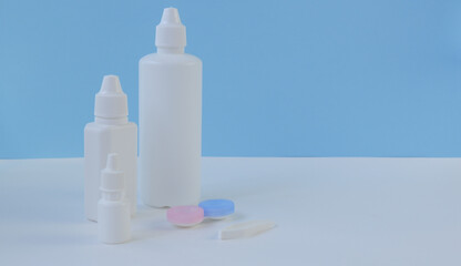 Accessories and products for the care of contact lenses on a white and blue background. Horizontal composition. Foreground.