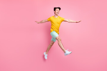Fototapeta na wymiar Profile photo of crazy careless active guy jump go look empty space wear yellow t-shirt isolated on pink background