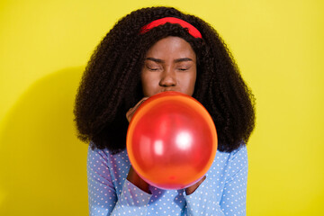 Photo of funky young dark skin positive woman blow air balloon festive decoration isolated on...