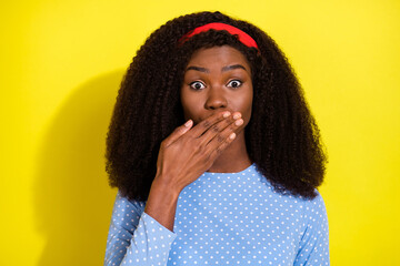 Photo portrait of curly girl shut mouth with hand keeping secret isolated on vivid yellow color...