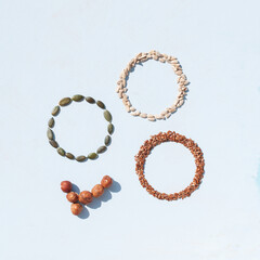 Circles made from different kinds of seeds on white background. Pumpkin seeds, sunflower seeds and linseed.
