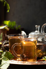 tea is poured into glass mugs. A teapot and a cup of tea stand on a copper tray next to raspberry leaves and berries