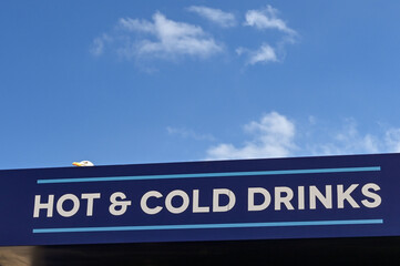 Obraz premium Sign above a seafront cafe selling hot and cold drinks. A seagull is peering over the top of the sign. No people.