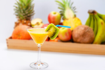 Fresh tropical fruits smoothie in a glass with a straw on a background of exotic fruits. Healthy food concept.