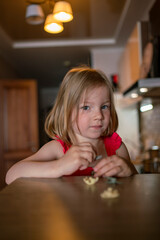 little girl is sitting at the table in the kitchen. child playing at home