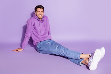 Portrait of attractive cheerful guy sitting spending time weekend day resting isolated over purple violet color background