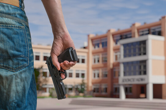 Gun control concept. Young armed man holds pistol in hand in public.