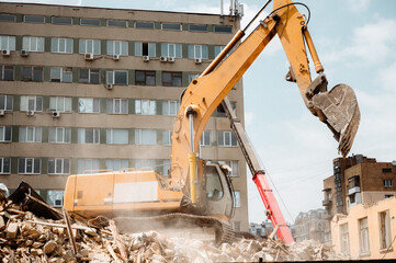 A construction bulldozer demolishes an old house on a clear day.
New construction site.
