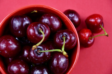 Sweet cherries in a red bowl top view stock images. Fresh cherries on a red background stock images. Sweet cherry fruit berries detail photo images