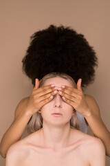 A dark-haired woman closing eyes to a blonde woman