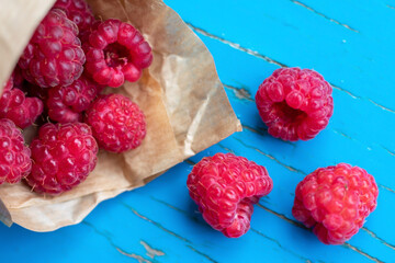 Heap of red raw ripe raspberries from paper cone, macro vegetarian food