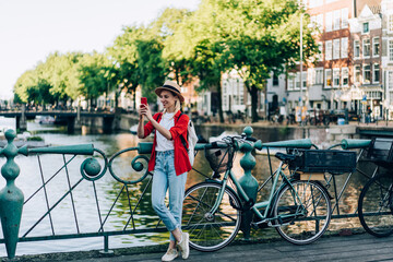 Happy female tourist using smartphone to take selfie on embankment - obrazy, fototapety, plakaty
