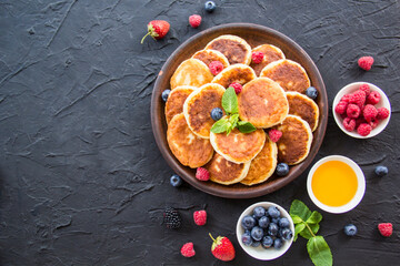 A healthy breakfast of cheese pancakes, berries, and honey. Creative atmospheric decoration