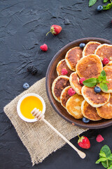 A healthy breakfast of cheese pancakes, berries, and honey. Creative atmospheric decoration