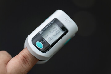 Asian Man measuring oxygen level with modern fingertip pulse oximeter using for measuring heart rate checking oxygen saturation level in the blood diagnosis of Coronavirus or COVID-19 medical concept