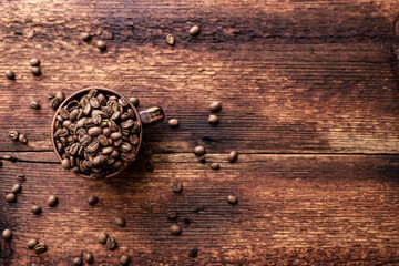 Coffee beans in a clay cup on a brown wooden old background.