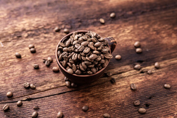 Coffee beans in a clay cup on a brown wooden old background.
