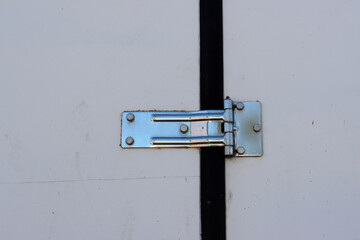 A steel door hinge screwed to a white wooden door.