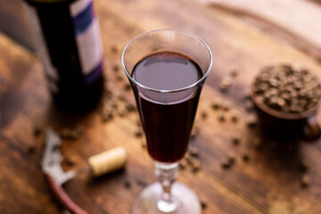 Glass with red wine and coffee beans on a brown old wooden background.