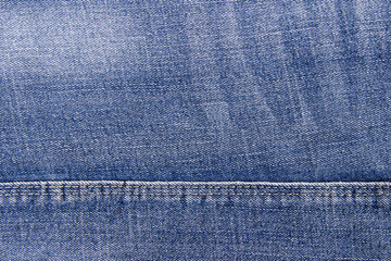 Blue denim background with a seam. Denim texture