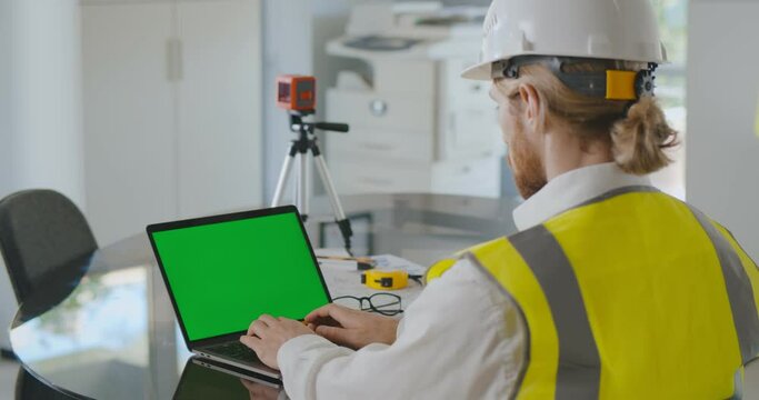 Over shoulder shot of civil construction engineer working with laptop at desk in office