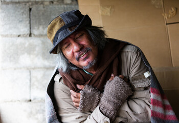 Portrait of Homeless man wear hat with beard, moustaches, sitting, close his eyes, smiling and cold