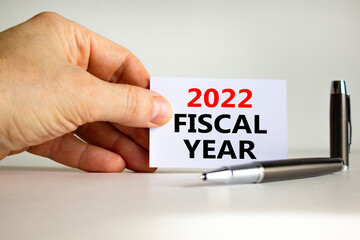 2022 fiscal new year symbol. White paper with words '2022 fiscal year' in businessman hand, metallic pen. Beautiful white background. Business and 2022 fiscal new year concept. Copy space.