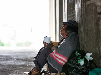 Homeless man sitting need money or food in an abandoned building or on street