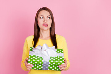 Photo portrait girl biting lip unhappy keeping present box on birthday party looking copyspace...