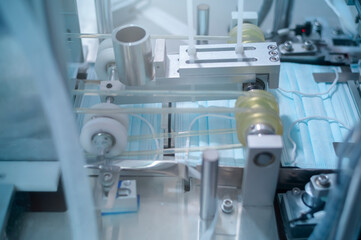 Close up of machine producing surgical mask in modern factory, Covid-19 protection and medical concept.