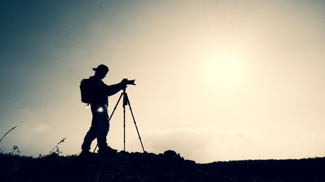 gesture silhouette Professional landscape travel photographer taking pictures on the mountain.