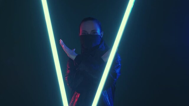Cyberpunk protest. No future. Prohibition warning. Red blue neon light dissatisfied woman in face buff rejecting with nope X crossed hands gesture with LED glow isolated on dark.