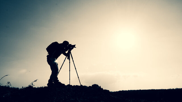 silhouette Professional landscape travel photographer taking pictures on the mountain.