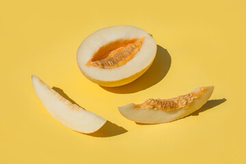 Sunny sliced melon with seeds on bright yellow background. Trendy photography with hard shadows.